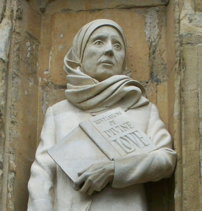 A stone statue of Julian of Norwich holding her "Revelations of Divine Love"